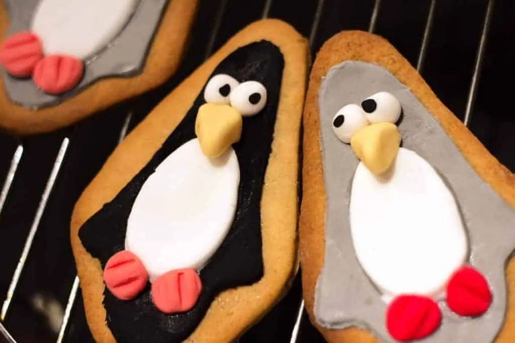 Two Cute Penguin Biscuits lying side by side with their eyes looking at each other.