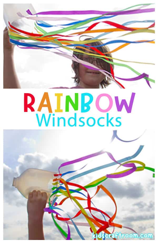 A child holding up a homemade rainbow windsock in the wind. The colored ribbons are blowing around.