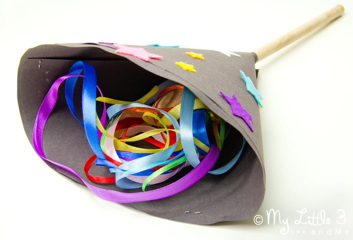 Showing how to use a homemade firework craft by tucking the ribbons inside.