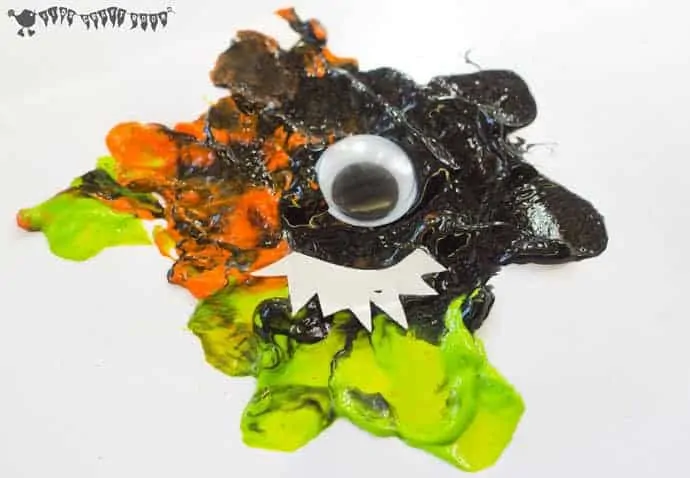 A black, green and orange Blow Painting Monster Craft with a wiggle eye. 