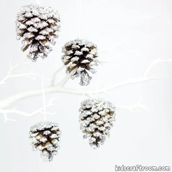 4 frosty pinecones hanging from a white faux tree branch.