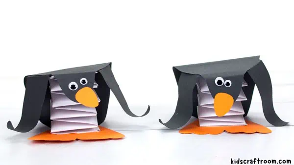Two pop up penguins standing side by side with their orange beaks pointing in opposite directions.