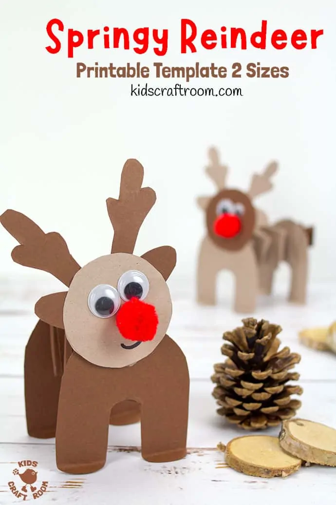 A dark brown accordion paper reindeer craft. He has a happy smile and a red pom pom nose. He's standing next to a pinecone and some wood slices.