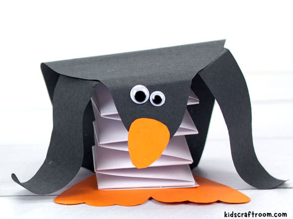 A close up of a pop up penguin showing that it's made of paper and has a paper spring inside.