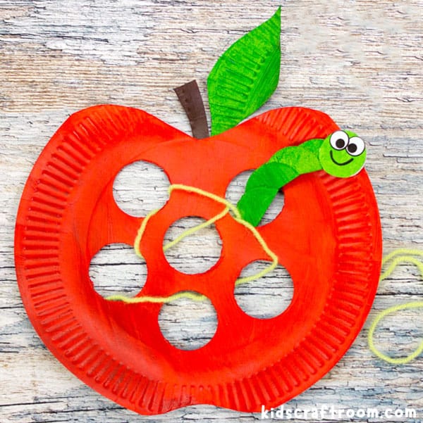 A close up of a Paper Plate Apple Lacing Craft for kids, showing the worm poking out of a hole.