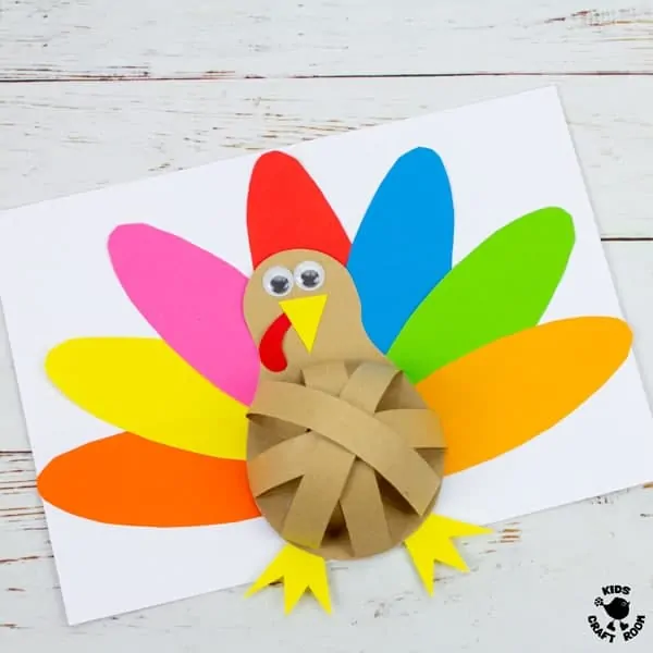 A close up of a finished turkey craft showing it's round belly that is made from arches of brown paper. Behind the turkey's body there is a fan of brightly coloured tail feathers.