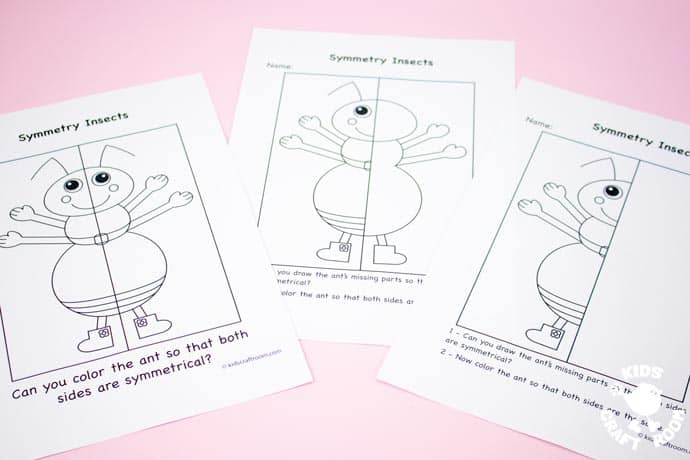 3 ant insect symmetry worksheets on a pink table top.