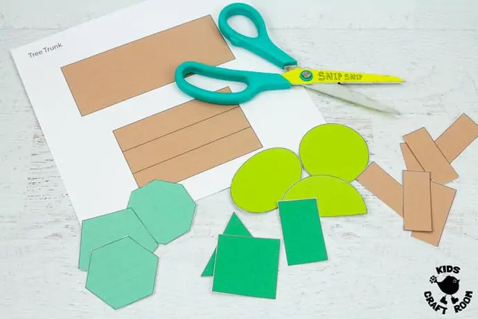 A summer shape tree template partially cut out, lying on a white table top with a pair of open scissors.
