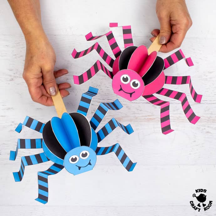 Walking Spider Puppet Craft in blue and pink being held above a white table top.