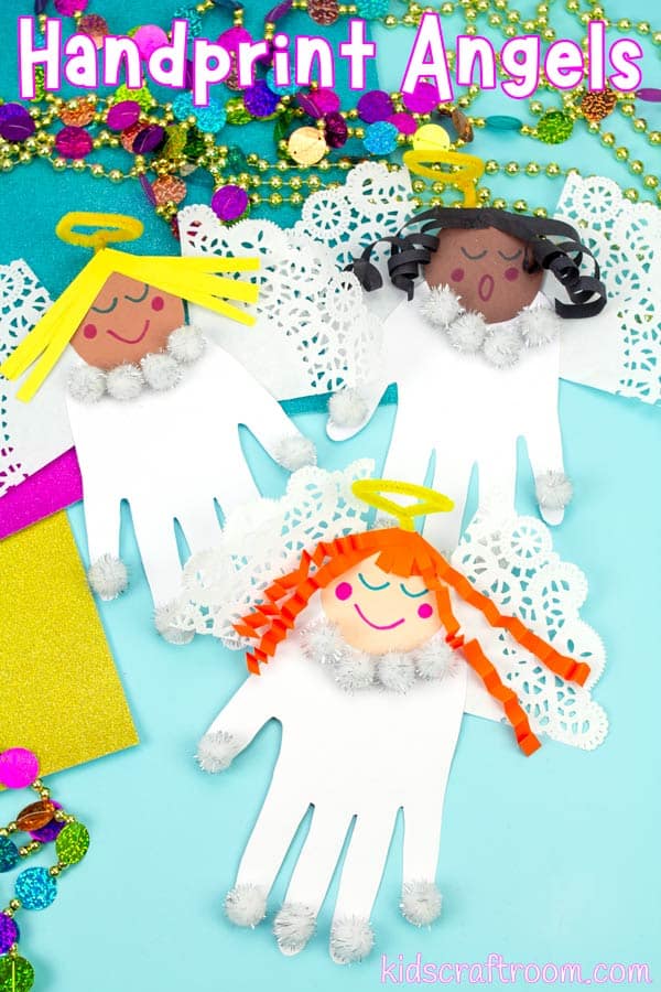 Portrait image of 3 handprint angels with different coloured hair on a blue tabletop with colourful Christmas decorations scattered about them. Overlaid with the text "Handprint Angels".