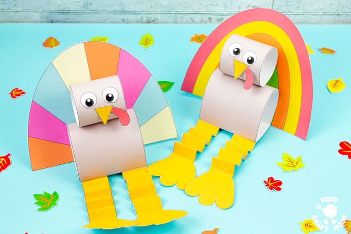 Two paper turkey puppets sitting side by side on a blue table top that's scattered with mini faux leaves.
