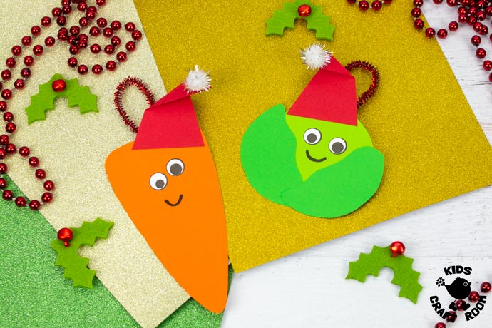 2 vegetable Christmas ornaments lying side by side on a table top. There is glitter wrapping paper behind them and felt holly leaves scattered around them.