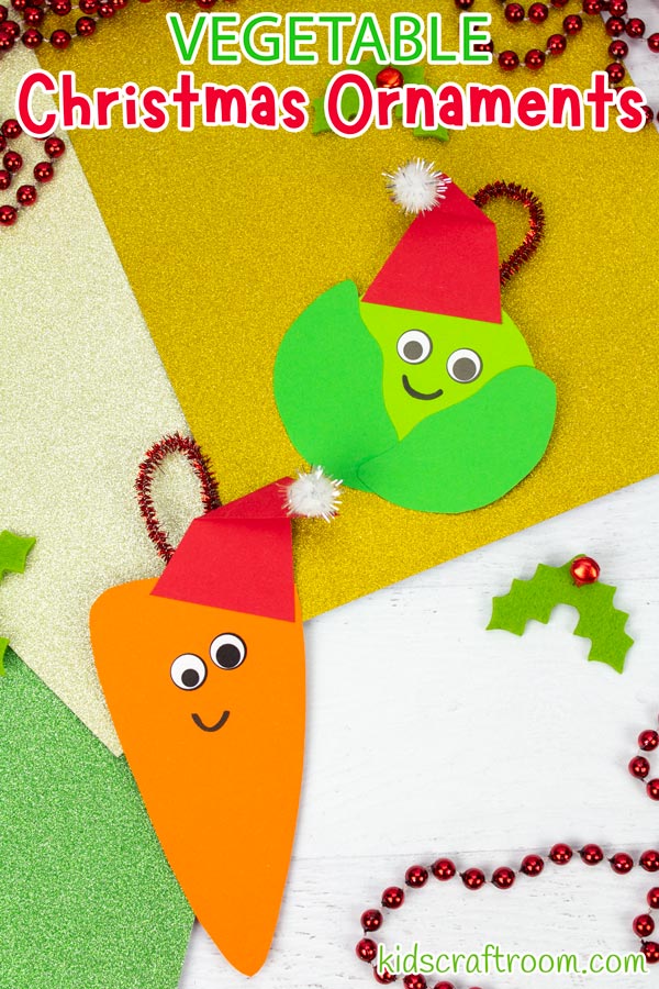 Two vegetable Christmas ornaments lying on a white table top with glitter wrapping paper under them and Christmas decorations scattered around.