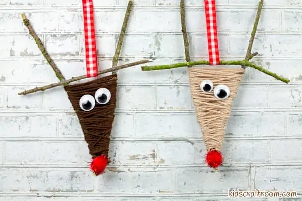 2 Yarn Wrapped Reindeer hanging against a background of white brick wall.