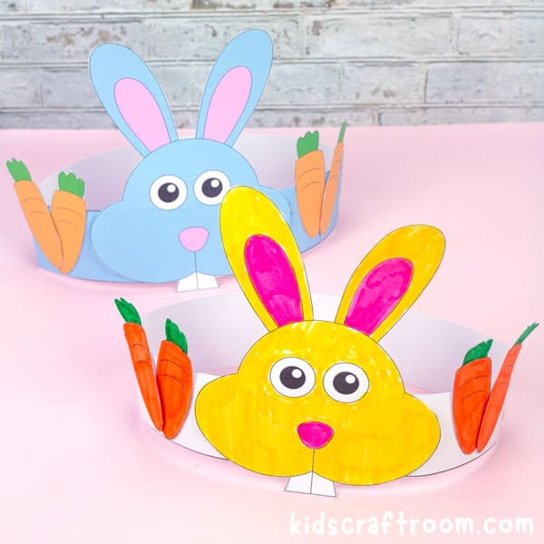 A yellow Easter Bunny Headband in the forground with a blue one in the background. Sitting on a pink table.