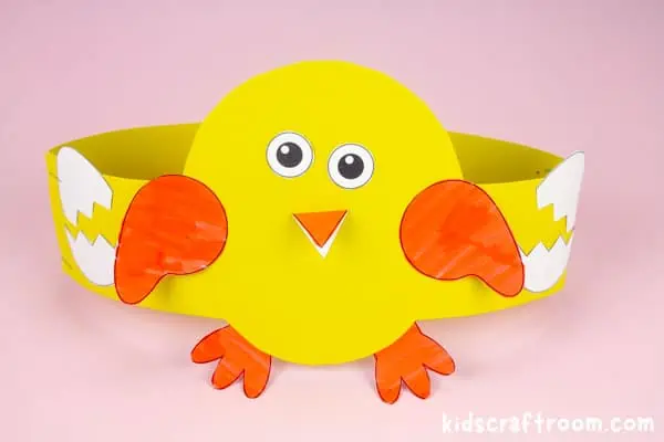 A yellow chick crown sitting on a pink tabletop.