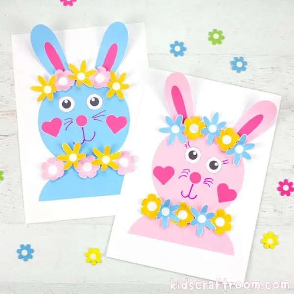 2 Flower Power Bunny Crafts, one blue, one pink. Lying side by side on a white tabletop with scattered flowers around them. 