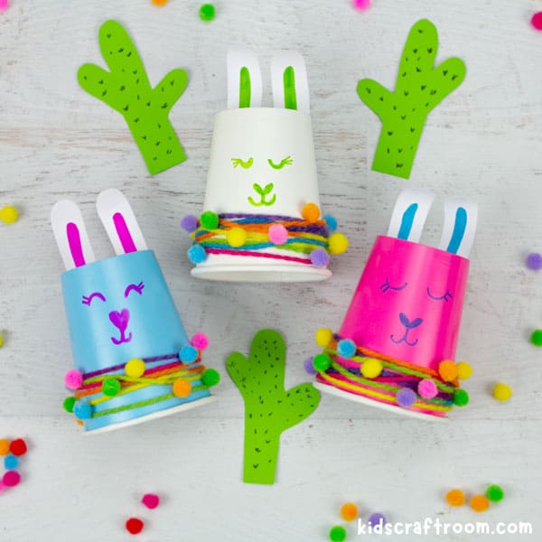 3 paper cup llama crafts lying on a tabletop. One blue, white and pink.