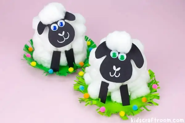2 finished paper cap sheep crafts side by side on a pink tabletop.