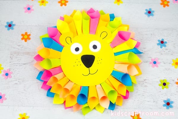 A sticky note lion craft lying on a table top surrounded by little scattered paper flowers. 