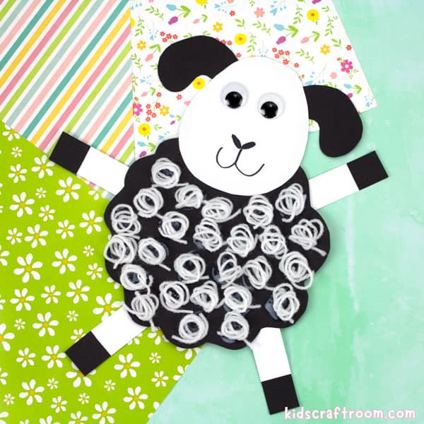 A woolly sheep craft lying on a selection of brightly coloured spring themed papers.