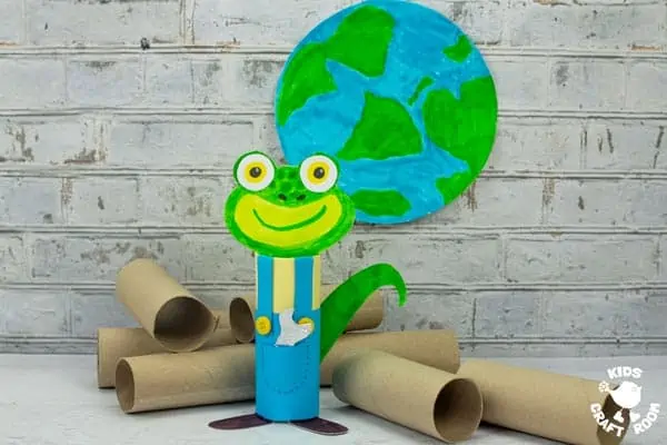 A gecko craft made from a cardboard tube standing on a white tabletop in front of lots of cardboard tubes.
