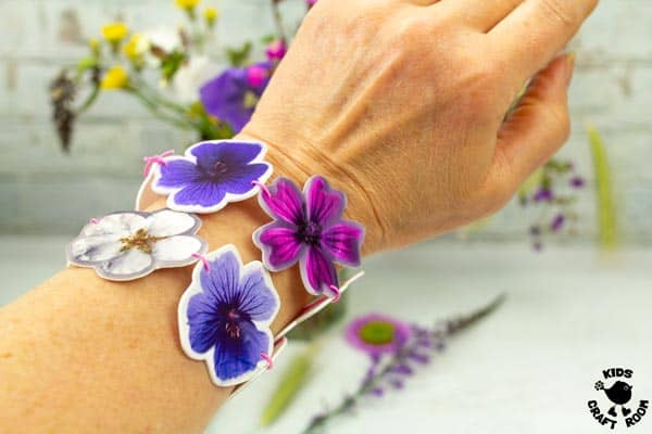 Shrink plastic flower bracelets being worn on a wrist.