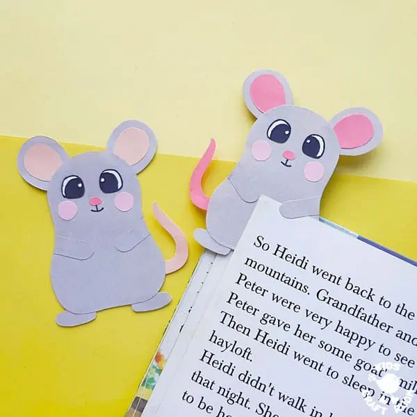 Two Mouse Bookmark Crafts on a yellow background. The right hand mouse is holding the page of a book.