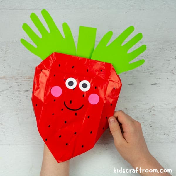 Strawberry Paper Bag Puppet being played with by two hands.
