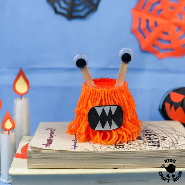 Hairy Paper Cup Monster Craft on a pile of books.