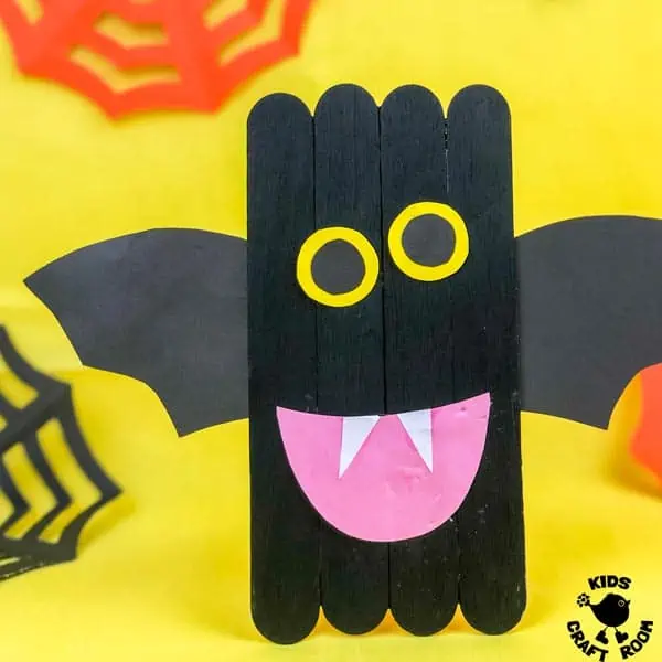 A square image of a Popsicle Stick Bat Craft in front of a yellow background. 