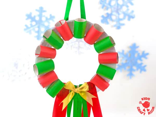 A Cardboard Tube Christmas Wreath Craft hanging against a background of blue snowflakes.