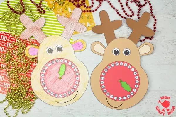 2 Reindeer Christmas Countdown Clocks lying on a table top. They are surrounded by Christmas gift wrap and decorations.