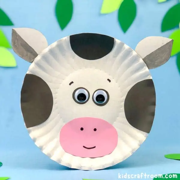 Close up of a Paper Plate Cow Craft For Kids on a blue background.