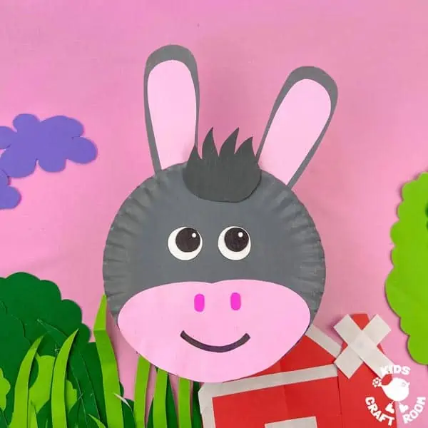 A paper plate donkey craft against a pink background.