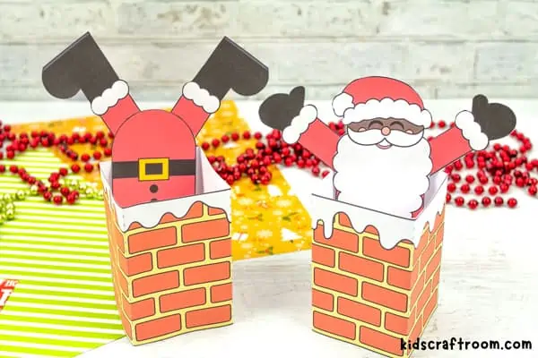 A close up of 2 Santa Stuck In The Chimney Crafts. The left has his feet poking out the right has his head poking out.