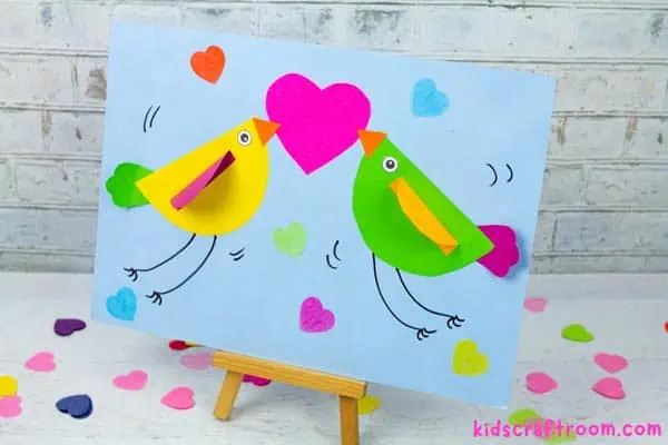 A close up of the love bird Valentine craft displayed on a wooden stand.