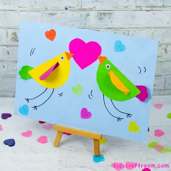 A finished Valentine love bird craft displayed on a wooden stand.