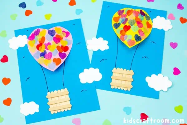 A pink and yellow Heart Hot Air Balloon Craft side by side on blue tabletop.