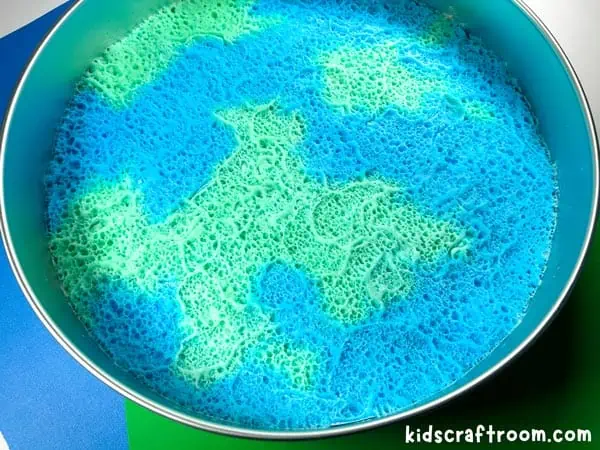 A finished Fizzy Earth Day Science Experiment in a round baking tray. It looks like the planet earth.