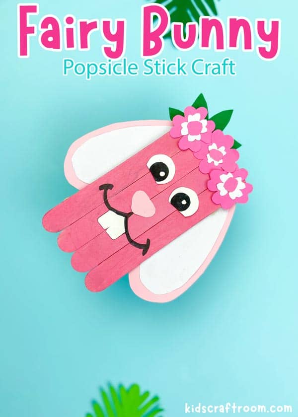 A fairy Bunny Popsicle Stick Craft lying diagonally on a blue background.
