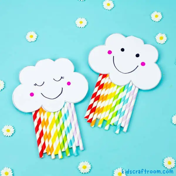 Two Rainbow Card Crafts lying on a blue background. One has eyes shut and one has eyes open.