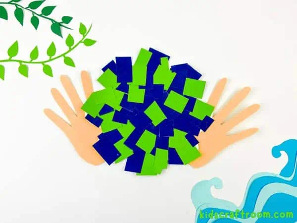 A Mosaic Handprint Earth Day Craft lying on a white background. Top left is decorated with paper leaves and bottom right is decorated with paper waves.