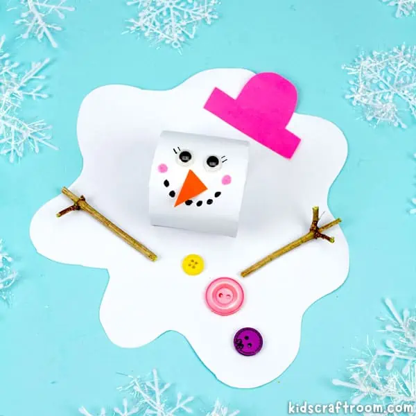 A close up of a melted snowman craft made from a white cardboard tube head and a paper body. It has googly eyes, a pink paper hat and orange paper nose. It has twig arms and buttons glued to its front.