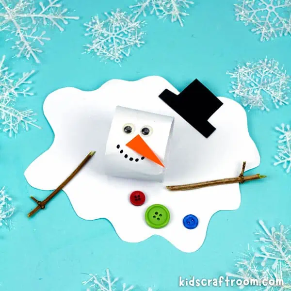 A close up of a melted snowman craft made from a white cardboard tube head and a paper body. It has googly eyes, a black paper hat and orange paper nose. It has twig arms and buttons glued to its front.