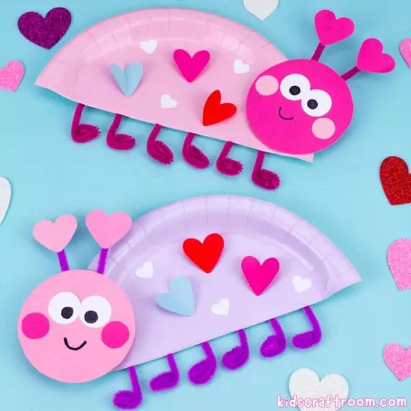 2 paper plate love bug crafts made from paper plates and decorated with paper hearts. One is pink and the other is purple. They have heart antennae and pipe cleaner feet.