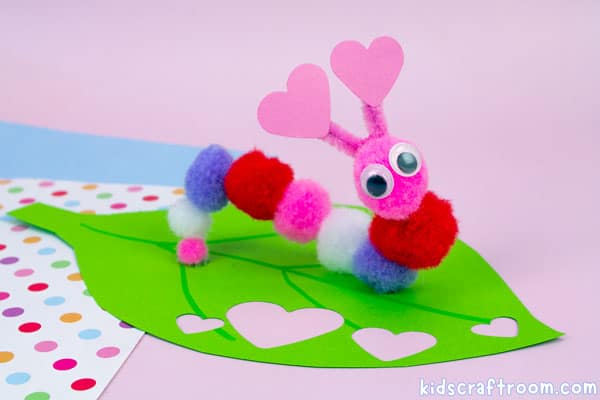 Ans easy caterpillar Valentine's Day craft for kids viewed from the side to see the arched body shape of the caterpillar made from pom poms.